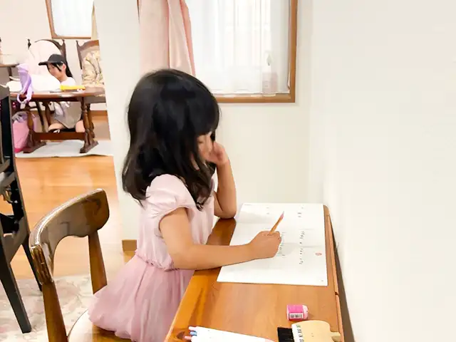 ピアノスタジオで兄弟のピアノ練習のあいだお勉強して待っている女の子
